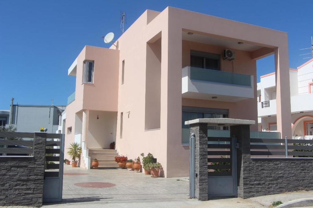 un gran edificio rosa con una puerta delante en Valentina's Luxe Apartment, en Mastichari