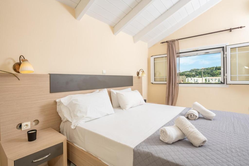 a bedroom with a bed with white sheets and a window at Premier Tsilivi in Tsilivi