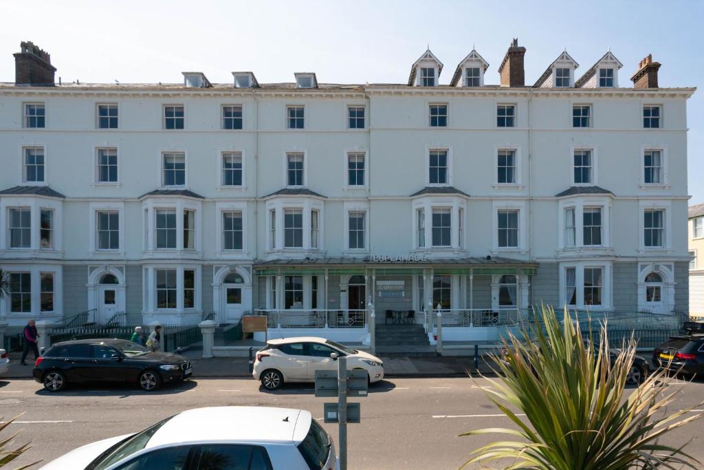 un grand bâtiment blanc avec des voitures garées dans un parking dans l'établissement Esplanade Hotel Llandudno, à Llandudno