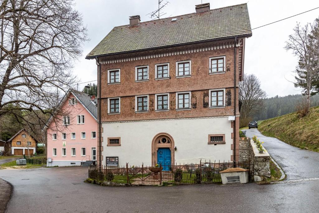 un grand bâtiment en briques avec une porte bleue dans l'établissement Altes Pfarrhaus, à Vöhrenbach