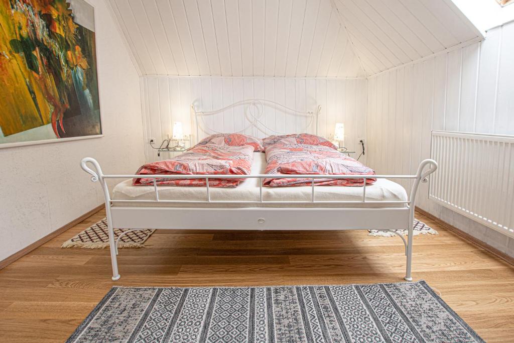 1 cama blanca con almohadas rojas en una habitación en Lichtenštejnské domky en Lednice