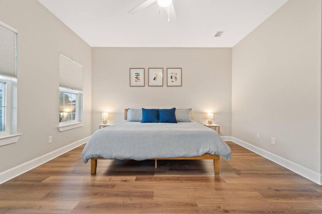 ein weißes Schlafzimmer mit einem Bett mit blauen Kissen in der Unterkunft Cheerful 3BR close to downtown + double balcony in Pensacola