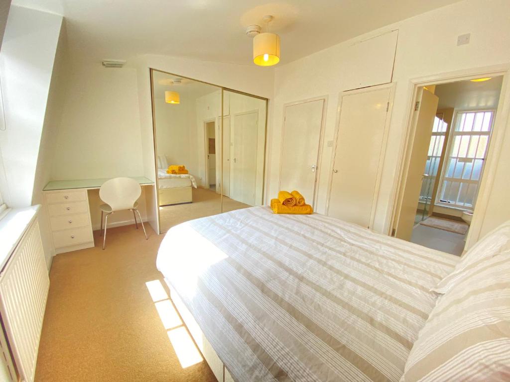 um quarto com uma grande cama branca e uma secretária em Cosy duplex in Central London em Londres