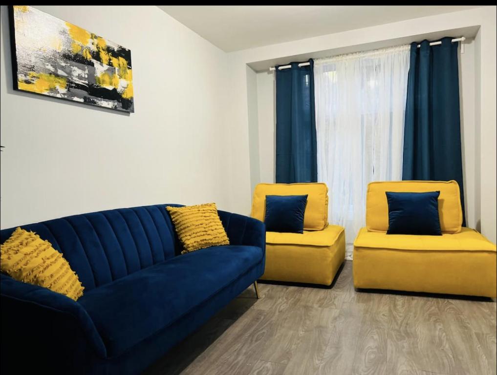 - un salon avec un canapé bleu et deux fauteuils jaunes dans l'établissement Fantastique 3 chambres modernes au cœur de la ville, à Montréal