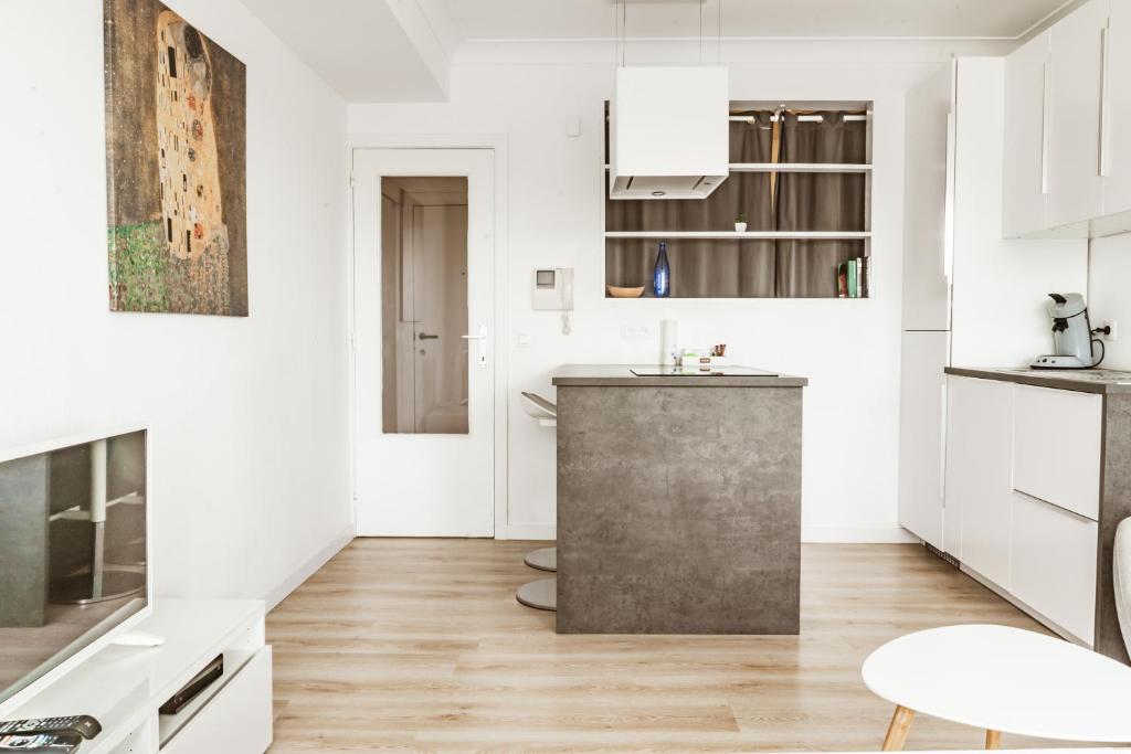 a kitchen with white cabinets and a sink and a table at Luxe studio in Ostend