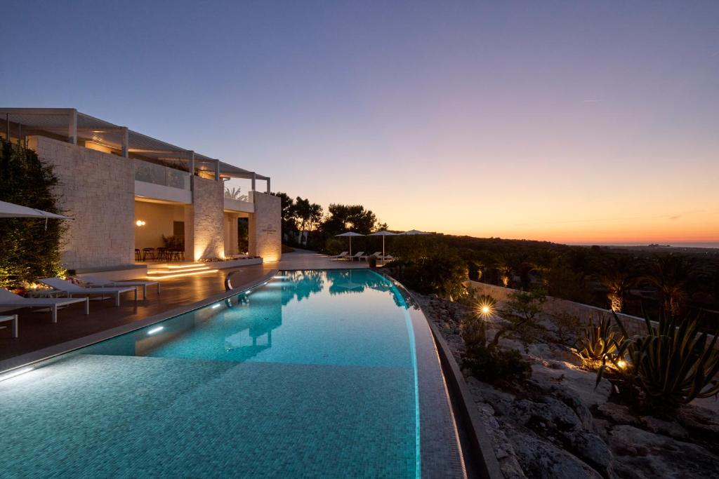 a large swimming pool in front of a house at Montegrottone Resort & Spa in Polignano a Mare