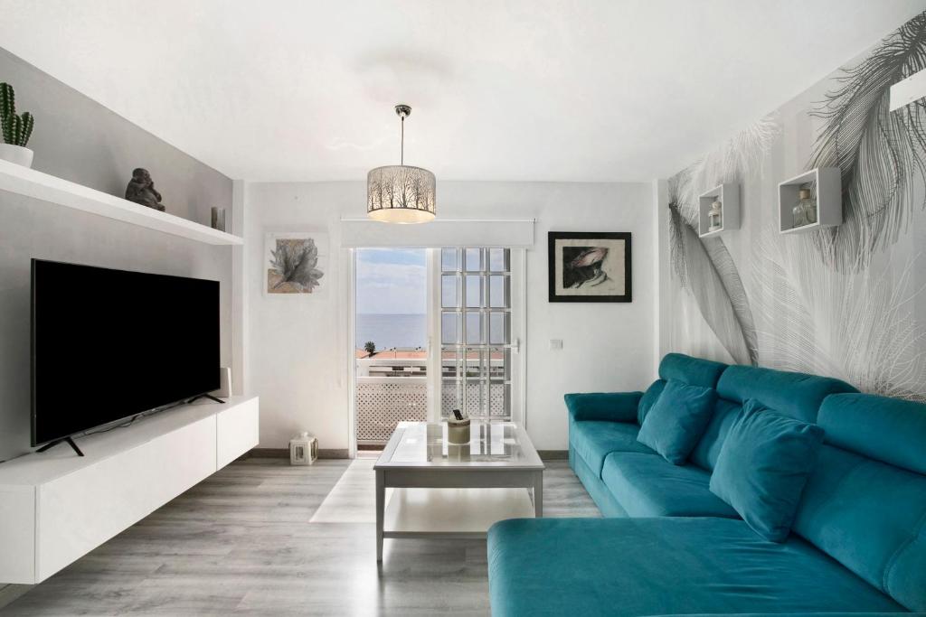 uma sala de estar com um sofá azul e uma televisão em yojalavi sunrise em Candelaria