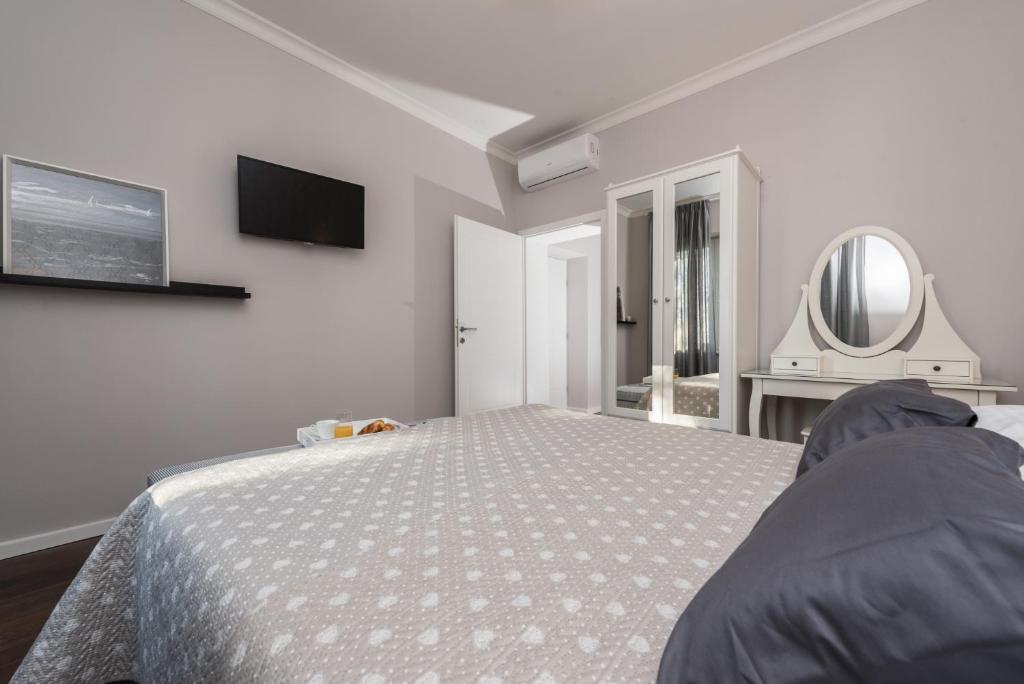 a white bedroom with a bed and a mirror at Sunset Beach Apartment in Zadar