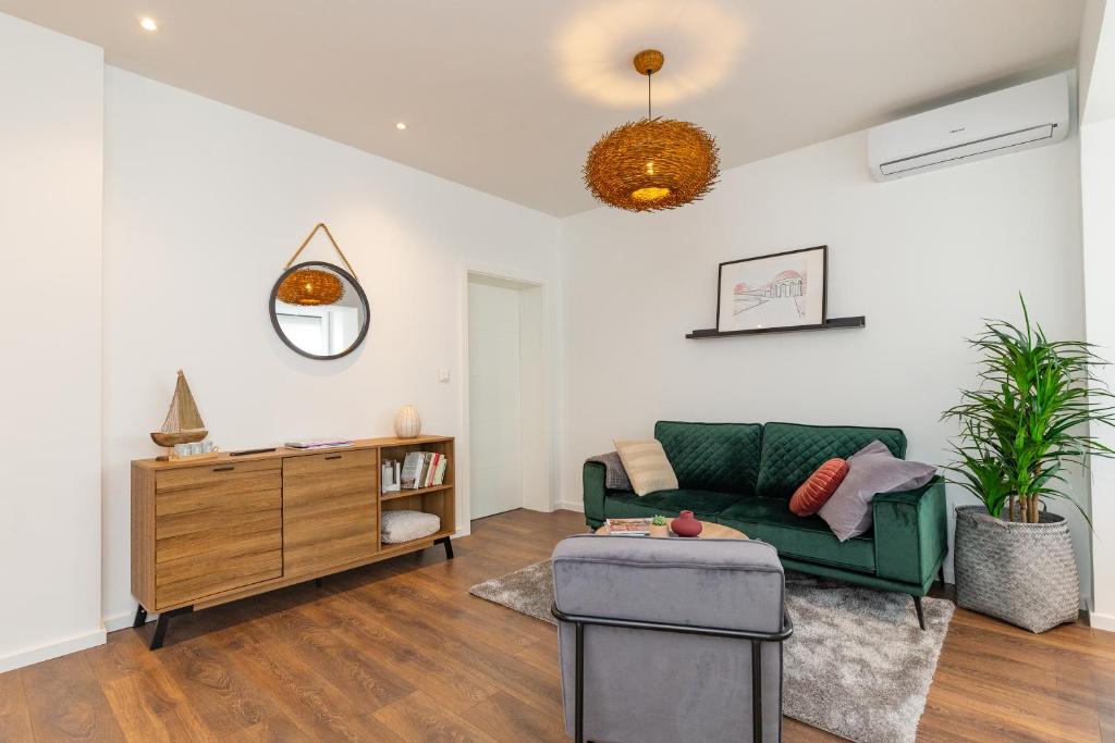 a living room with a green couch and a table at Sunset Beach Apartment in Zadar