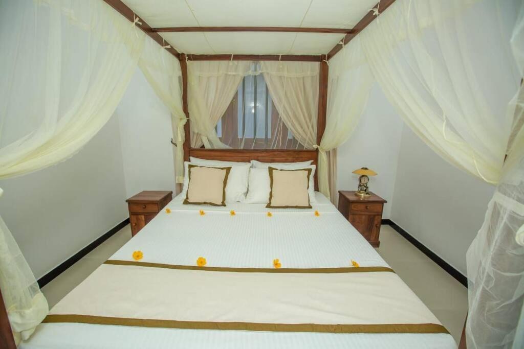 a bedroom with a large bed with white curtains at Greenway Apartment in Galle