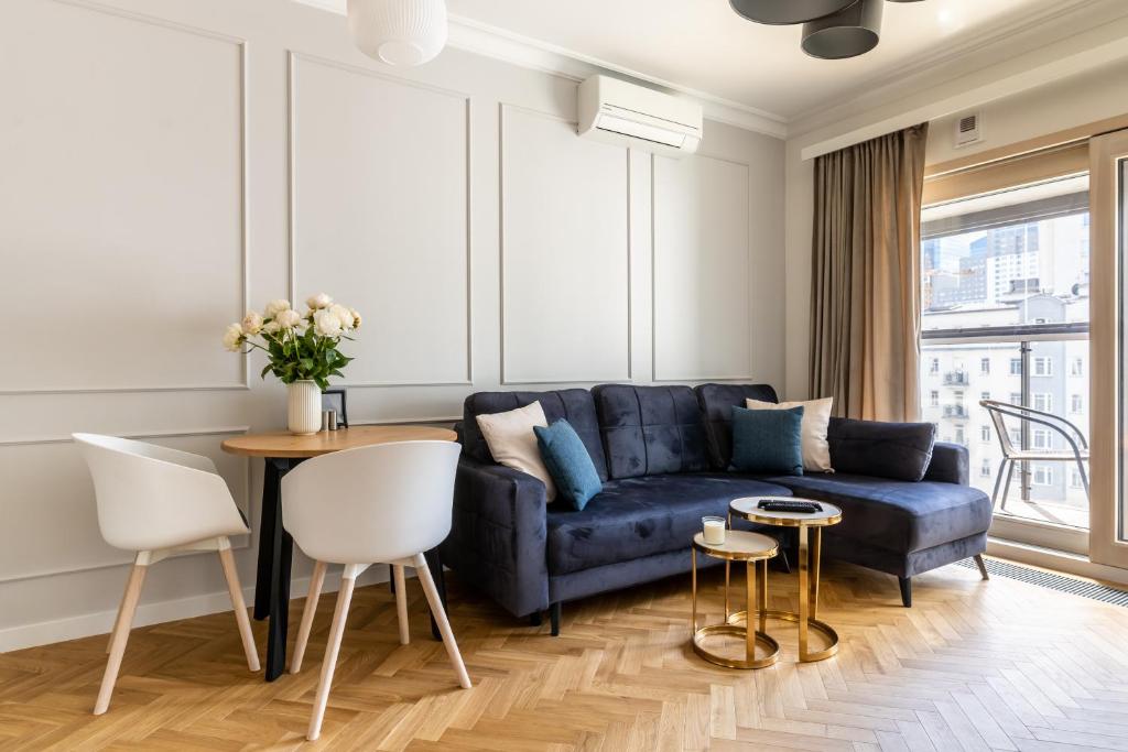 a living room with a blue couch and a table at Golden Apartments Warsaw - Mennica Residence in Warsaw