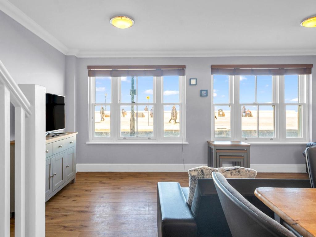 uma sala de estar com um sofá, uma mesa e janelas em Pass the Keys Sunset Cottage Luxury Home On The Seafront em Herne Bay