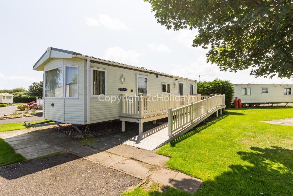 a mobile home in a yard with a porch at 6 Berth, Wheelchair Adapted Caravan At Southview Holiday Park Ref 33084s in Skegness
