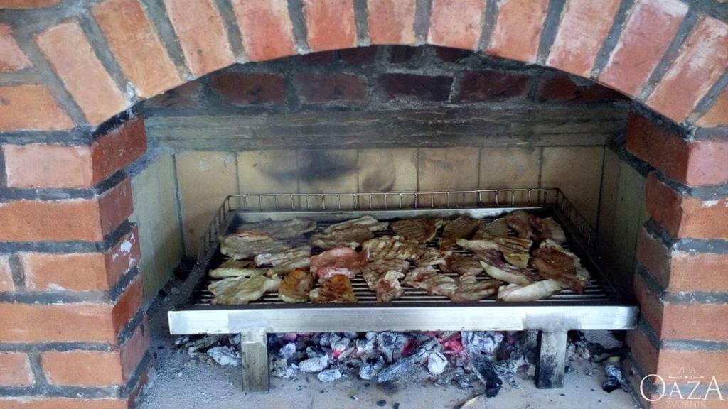 a brick oven with many different types of food on it at Vila Oaza - Zvorničko jezero in Zvornik