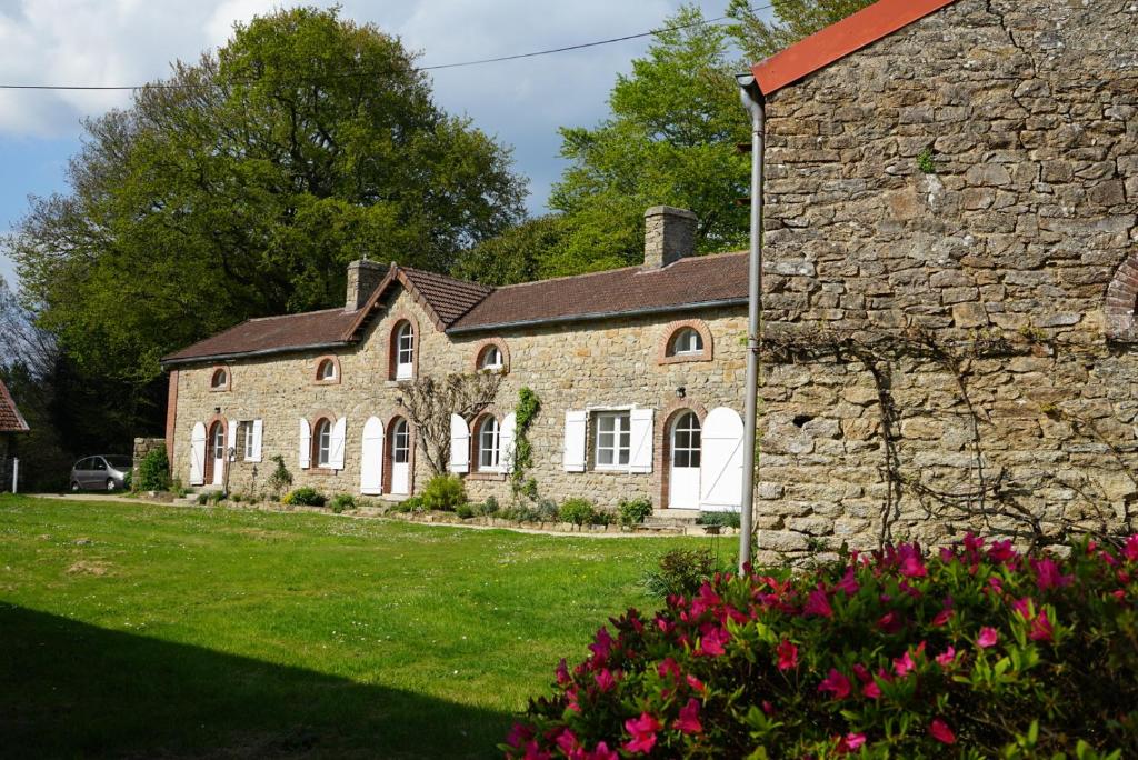 una casa de piedra con flores rosas delante de ella en Les Jardins de Bathilde - Au sein du Château de Bothané, en Guidel