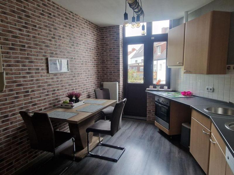 a kitchen with a table and chairs and a brick wall at Küstenliebe in Bremerhaven