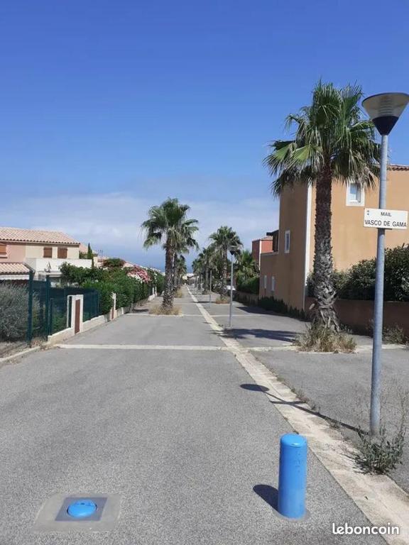 une rue vide avec des palmiers et un panneau de rue dans l'établissement Villa à 5 minutes à pieds de la mer, à Fleury