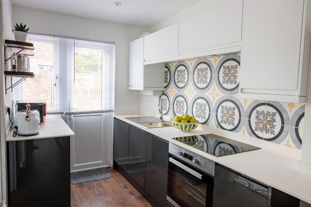 a kitchen with white cabinets and a patterned wall at Isca House, private garden, close to city center, the Quay, free wifi in Exeter