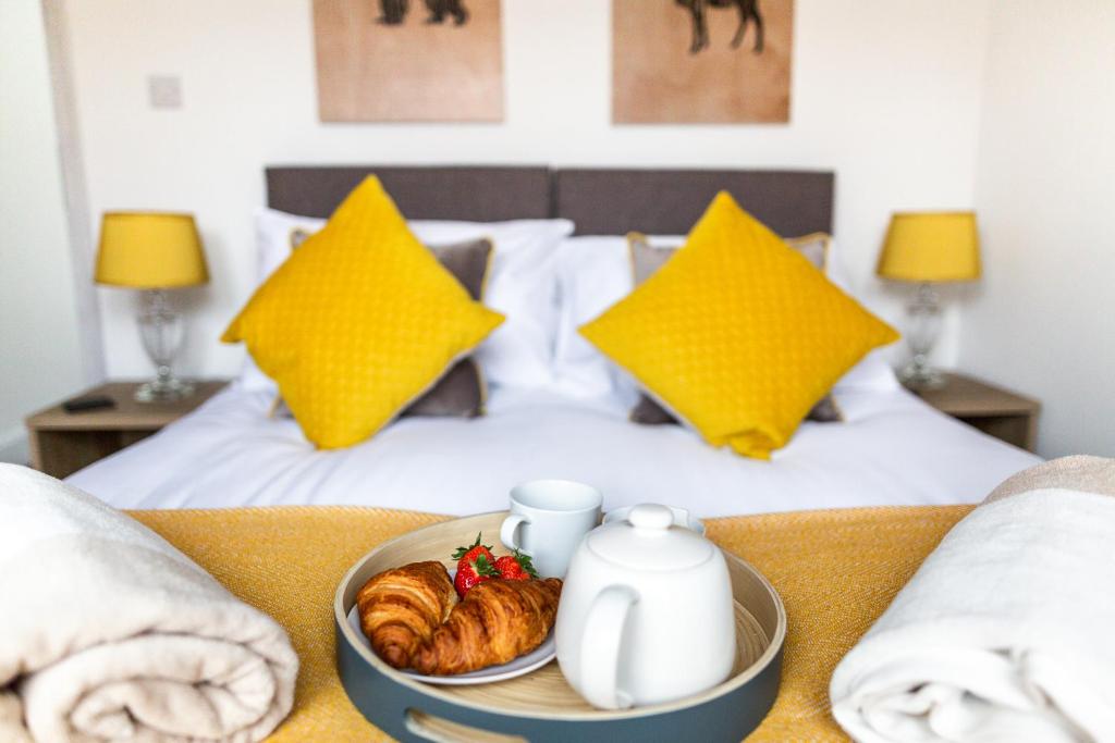 ein Frühstückstablett mit Croissants und Tee auf dem Bett in der Unterkunft Isca House, private garden, close to city center, the Quay, free wifi in Exeter