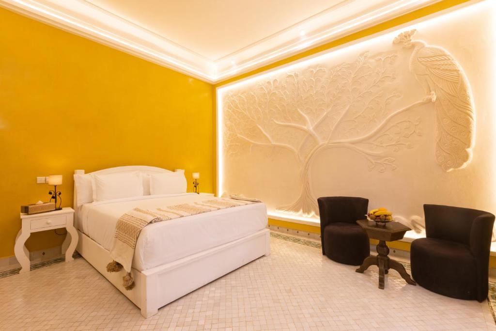 een slaapkamer met een wit bed en 2 stoelen bij Albakech Boutique Hôtel & Spa in Marrakesh