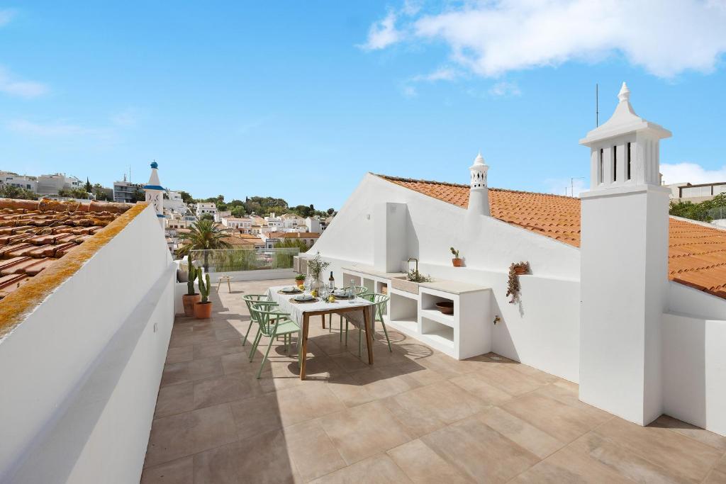 - une terrasse avec une table et des chaises dans un bâtiment blanc dans l'établissement Casa Helena, à Ferragudo