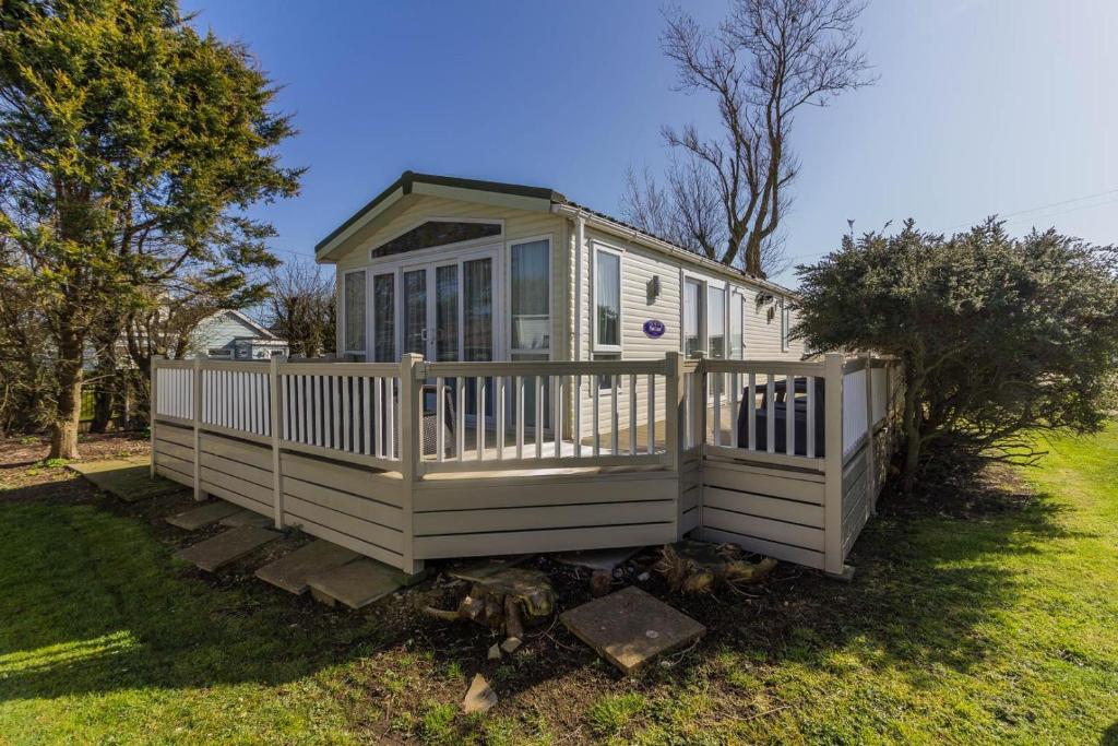 a white house with a fence in a yard at Luxury Caravan Nearby The Beautiful Scratby Beach In Norfolk Ref 50001a in Great Yarmouth