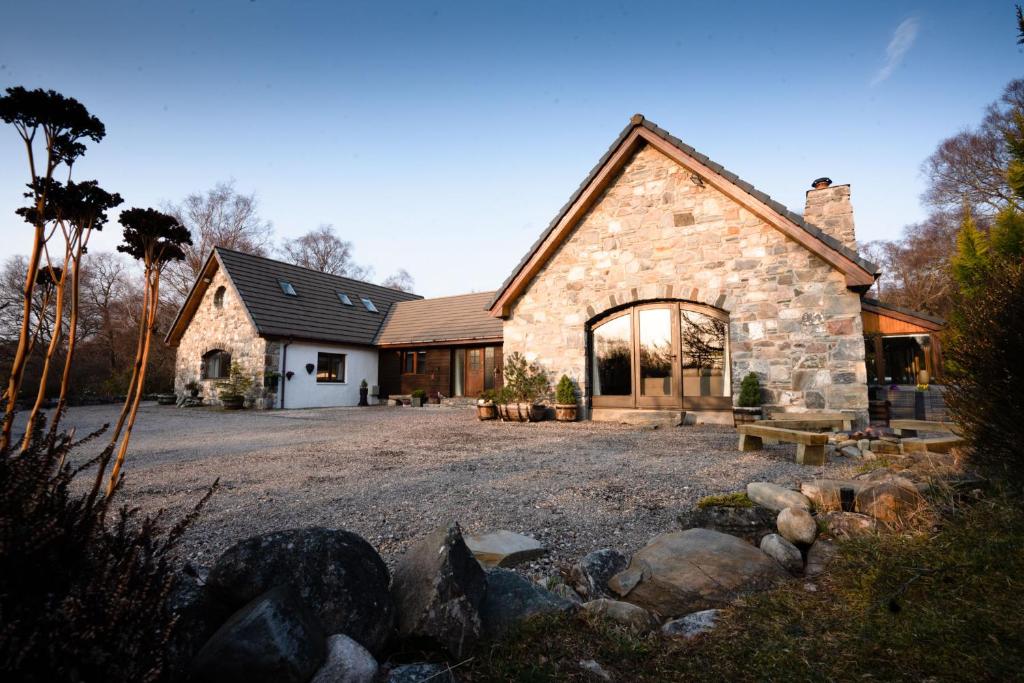 una casa de piedra con un gran patio delante en The Wilds - Seasgair Lodges en Kingussie