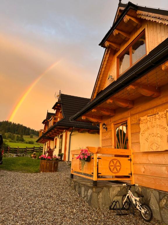 a rainbow in the sky behind a wooden house at Domki Na Stoku in Czarna Góra