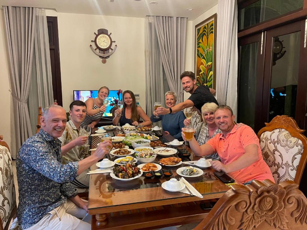 a group of people sitting around a table eating food at Danang Pool Villas Resort & Spa My Khe Beach in Da Nang