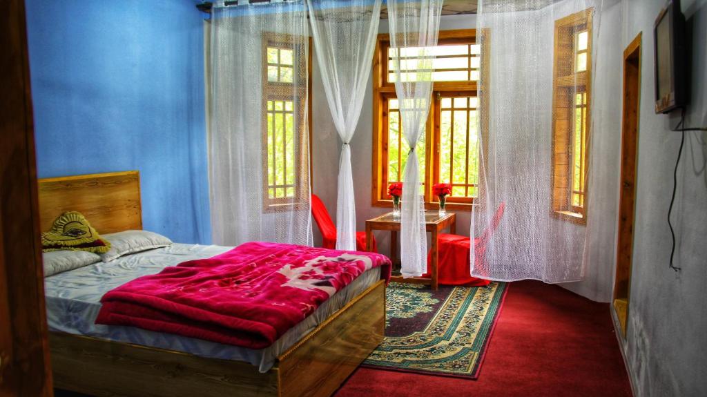 a bedroom with a bed with a red blanket at Rakaposhi Amin Hotel & Restaurant Pissan Hunza Nagar Gilgit Baltistan in Gilgit