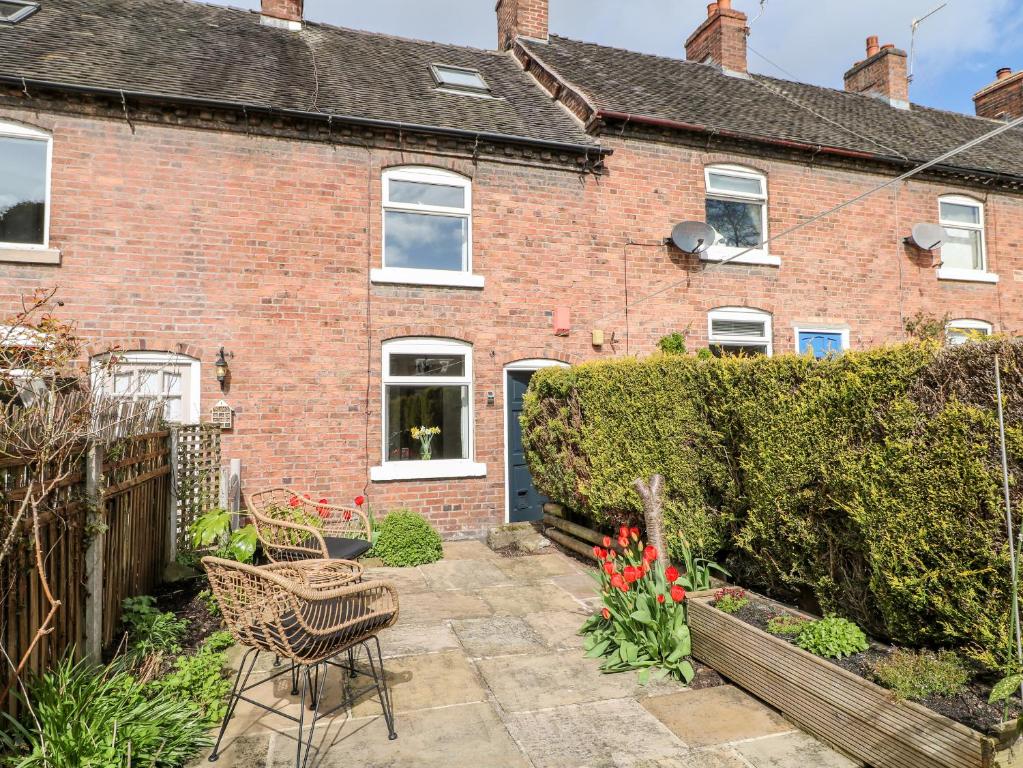 a brick house with a patio in front of it at 13 The Square in Oakamoor