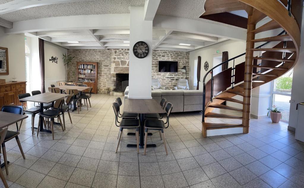 Gîte de Manehouarn في Plouay: غرفة طعام بها طاولات وكراسي ودرج حلزوني