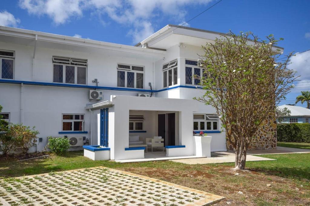 a white house with blue accents at 3 min walk to beach - Blue Waters Apt 2 apts in Bridgetown
