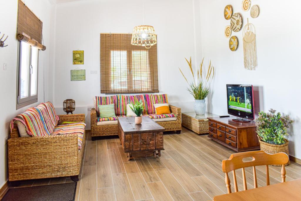 a living room with wicker furniture and a tv at Galatia's House in Kouklia