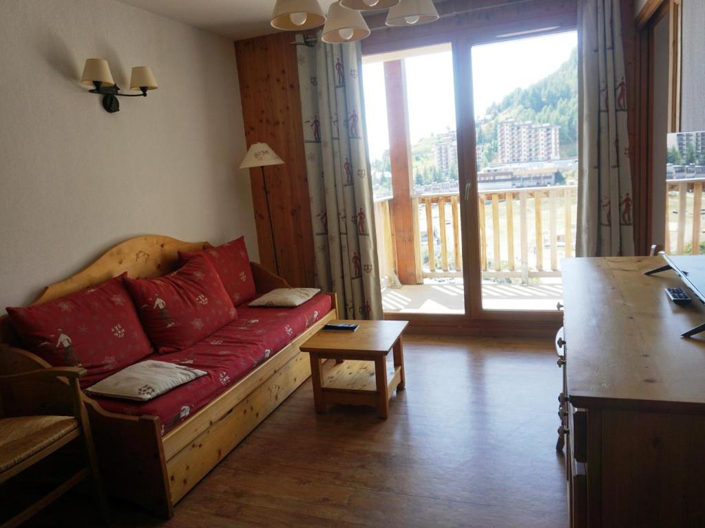 - un salon avec un canapé rouge et une grande fenêtre dans l'établissement Appartement 3 Pièces avec Piscine, Parking et Wi-Fi à Orcières Merlette - FR-1-636-28, à Orcières