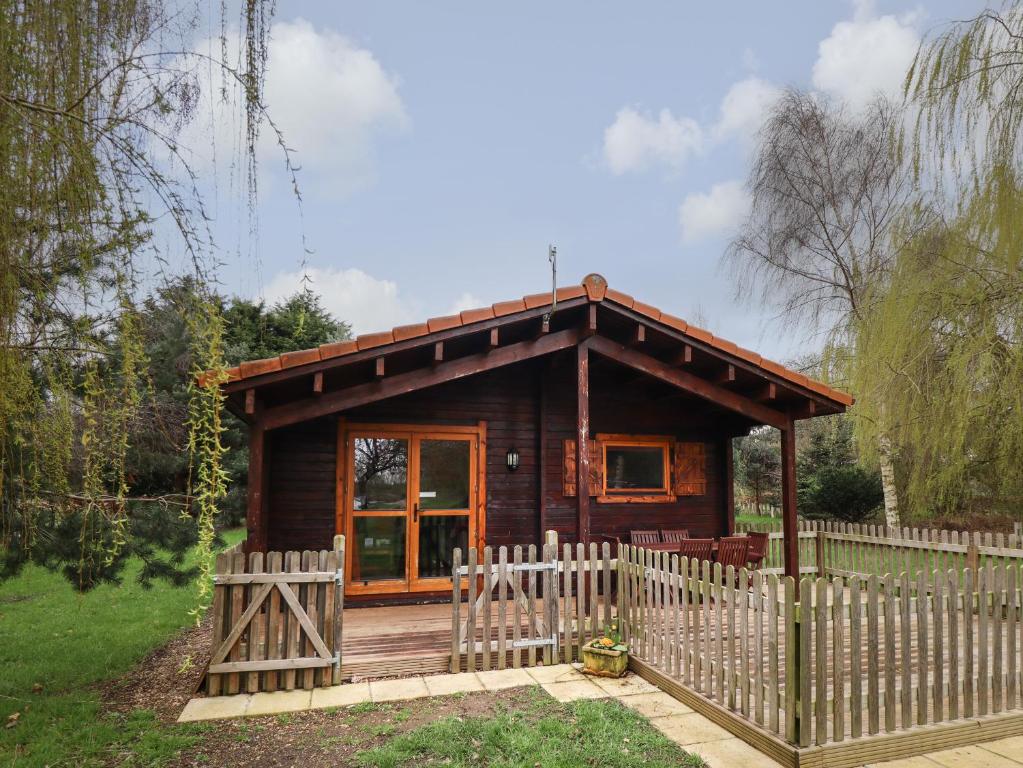 a small wooden cabin with a wooden fence at Teal Lodge in Market Rasen