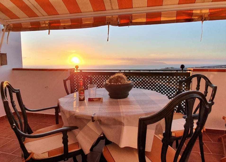 een tafel en stoelen op een balkon met uitzicht op de zonsondergang bij Apartamento Vista Atlántico in Adeje