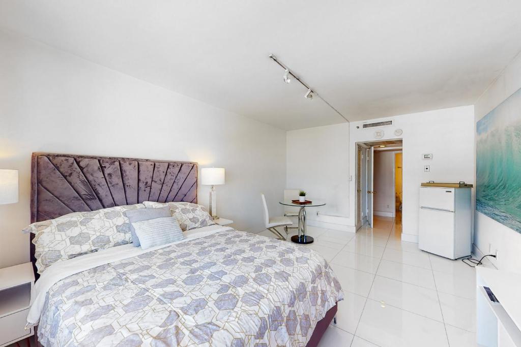 a white bedroom with a large bed and a kitchen at Decoplage Paradise - Unit A in Miami Beach