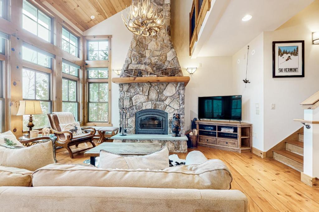 una sala de estar con 2 sofás y una chimenea de piedra. en Vermont Mountain Chalet, en Stratton