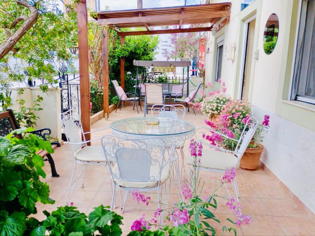 Choudetsi的住宿－Filoxenia，一个带玻璃桌、椅子和鲜花的庭院