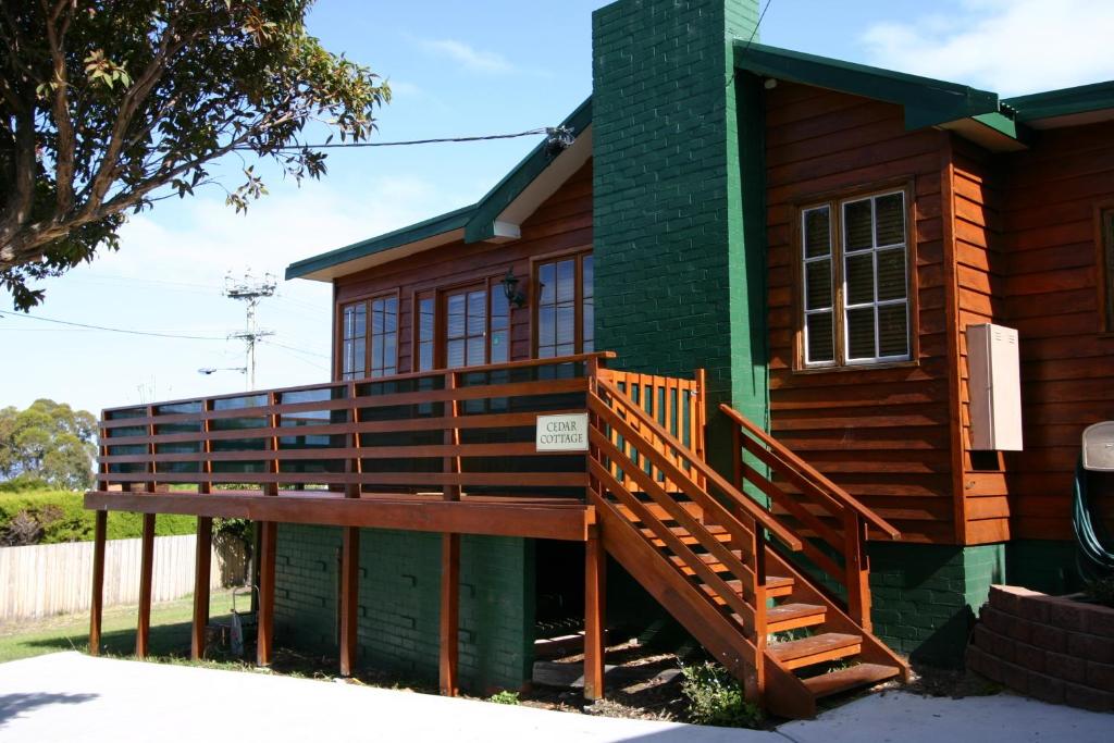 una casa con porche y terraza en Cedar Cottages Blackmans Bay, en Kingston