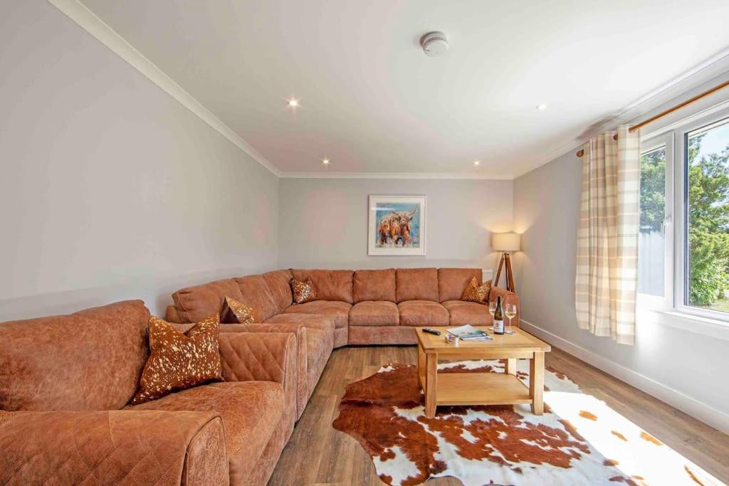 a living room with a brown couch and a table at Cuilreigh, North Connel in Oban