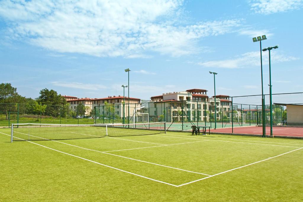 a tennis court with a tennis net and some buildings at Green Life Apartments Sozopol in Sozopol