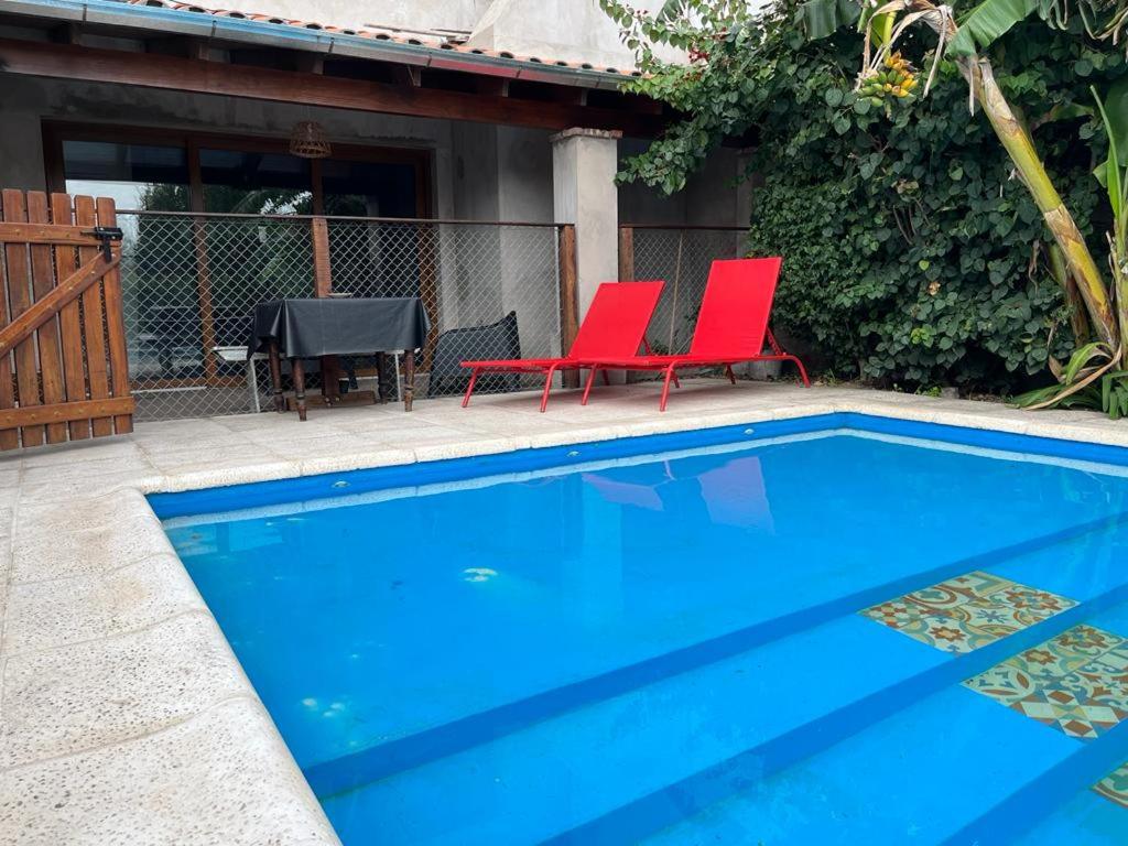 two red chairs sitting next to a swimming pool at El Descanso Casa de retiro in Tandil