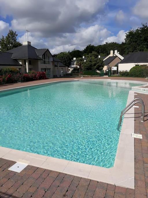 une grande piscine bleue devant une maison dans l'établissement Les cottages du golf à Ploemel, à Ploemel