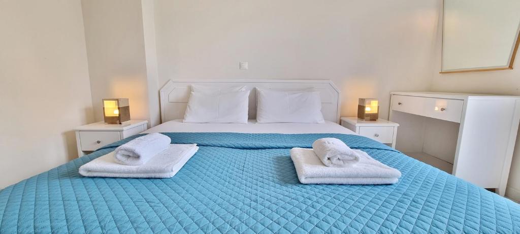 a bedroom with a blue bed with towels on it at Bungalow White Apartments in Polykhrono