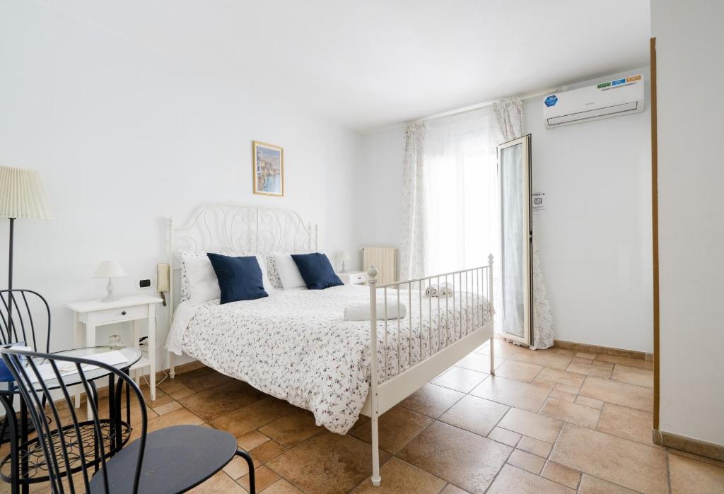 a white bedroom with a white bed with blue pillows at Bella Bari in Bari