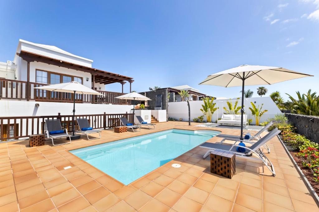une maison avec une piscine et un parasol dans l'établissement Lanzarote Villa Ascanio, à Playa Blanca
