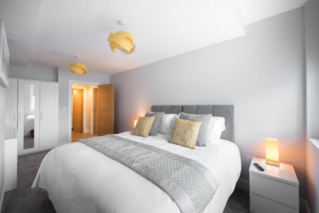 a white bedroom with a large white bed with pillows at S/KING BED ONE BEDROOM FLAT in Brentwood