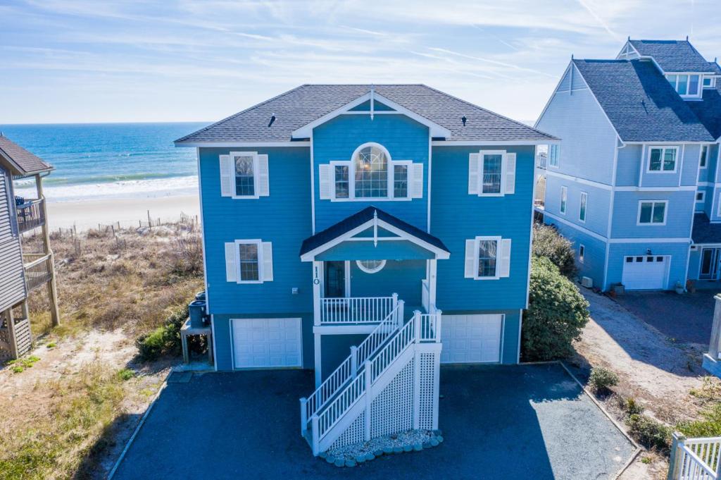 een blauw huis met de oceaan op de achtergrond bij 110 N Permuda Wynd in North Topsail Beach